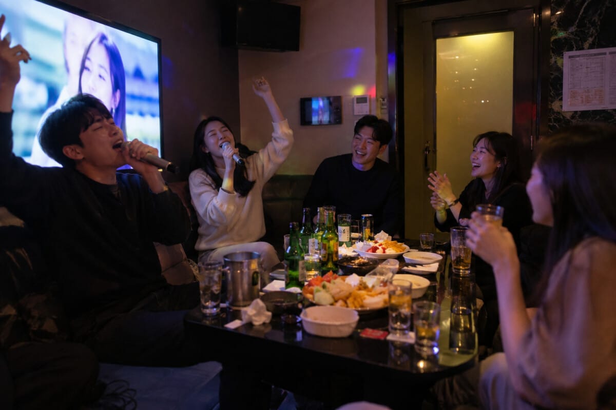 Friends singing in a private noraebang room during a late-night Seoul outing