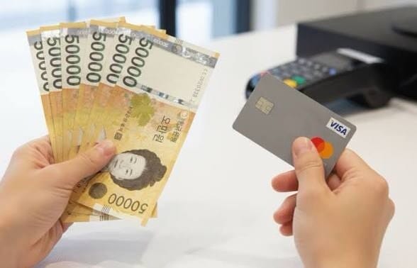 Korean won banknotes and an international credit card held at a payment counter