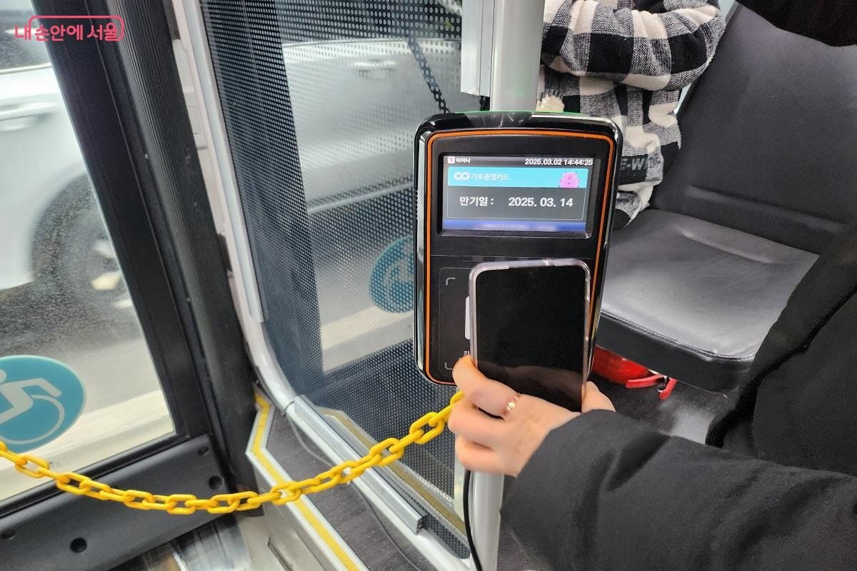 Passenger tapping a transportation card at the rear door reader on a Seoul bus
