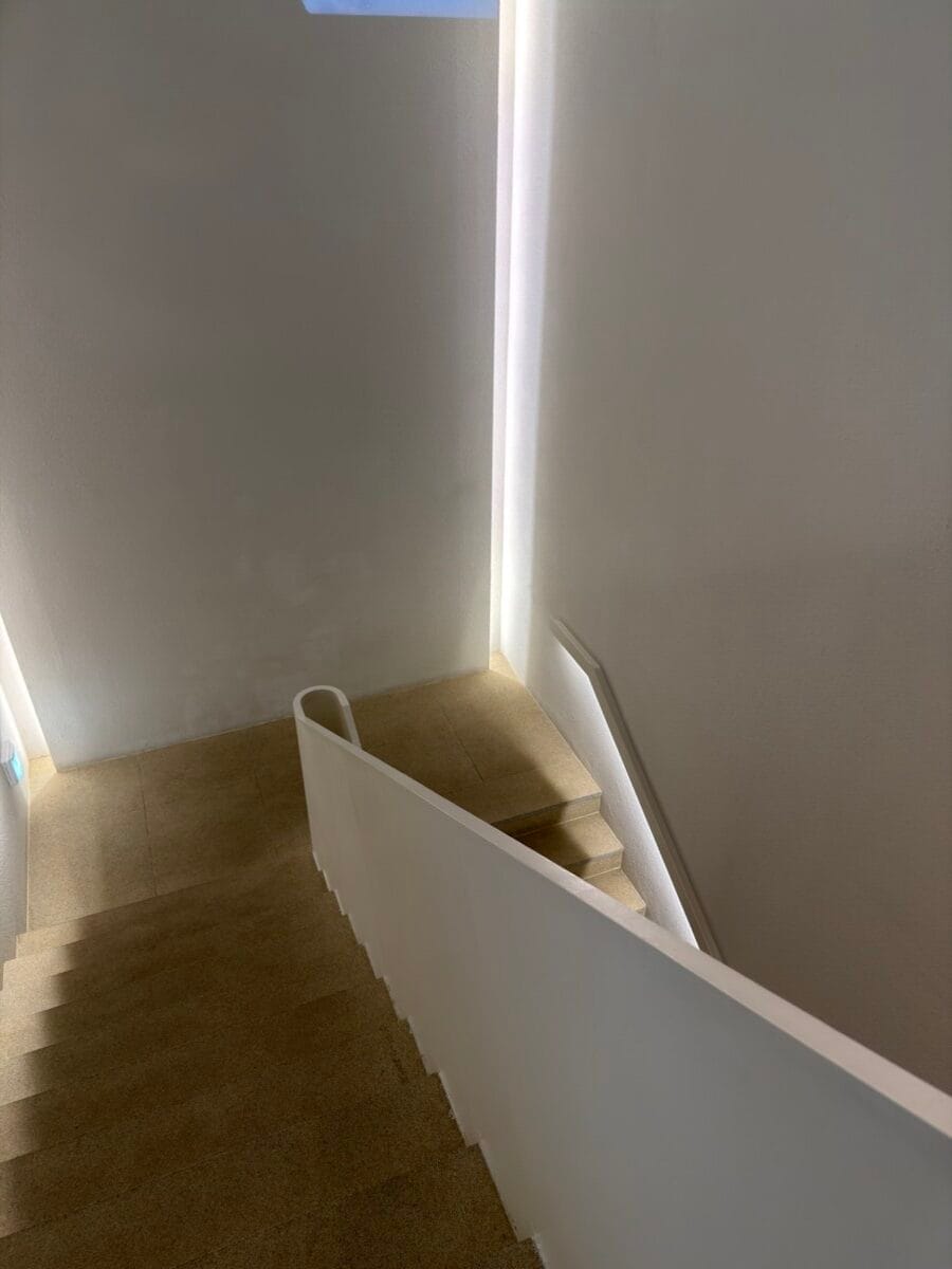 Minimal white stairway inside Blackish Red Cafe in Aewol