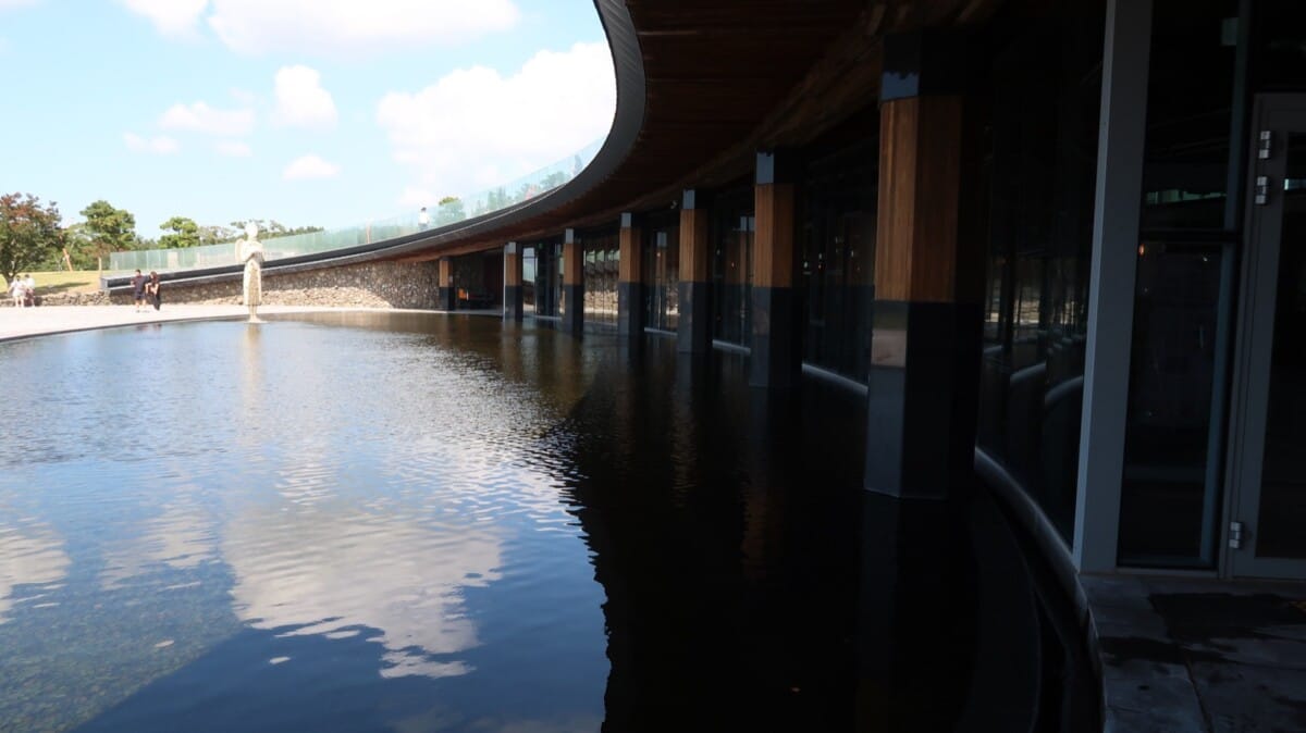 Curved Jejudang Bakery Cafe building beside a large water feature in Jeju Island