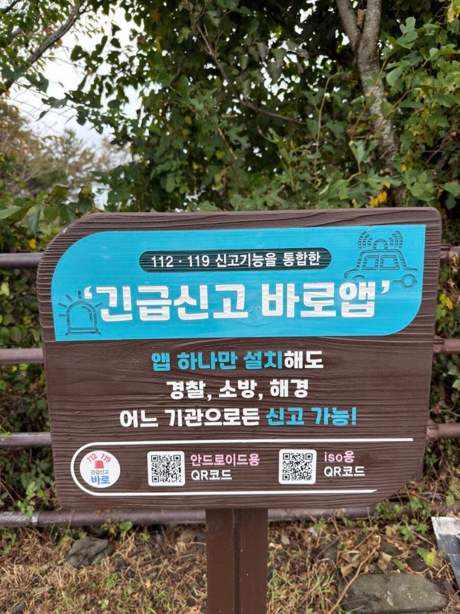 Emergency reporting app sign near Nokkome Oreum trail